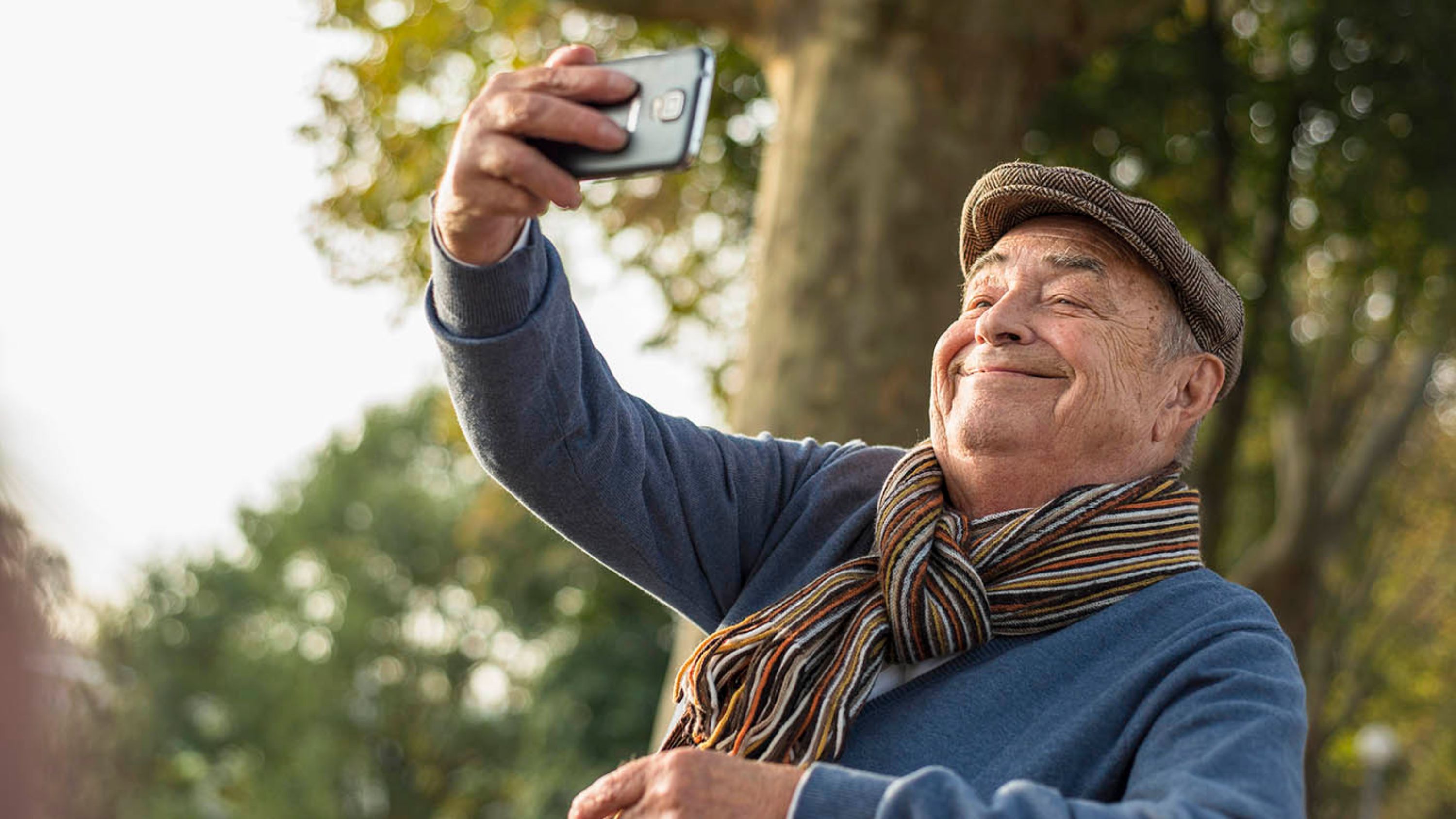 Ein älterer Herr macht ein Selfie mit dem Smartphone.