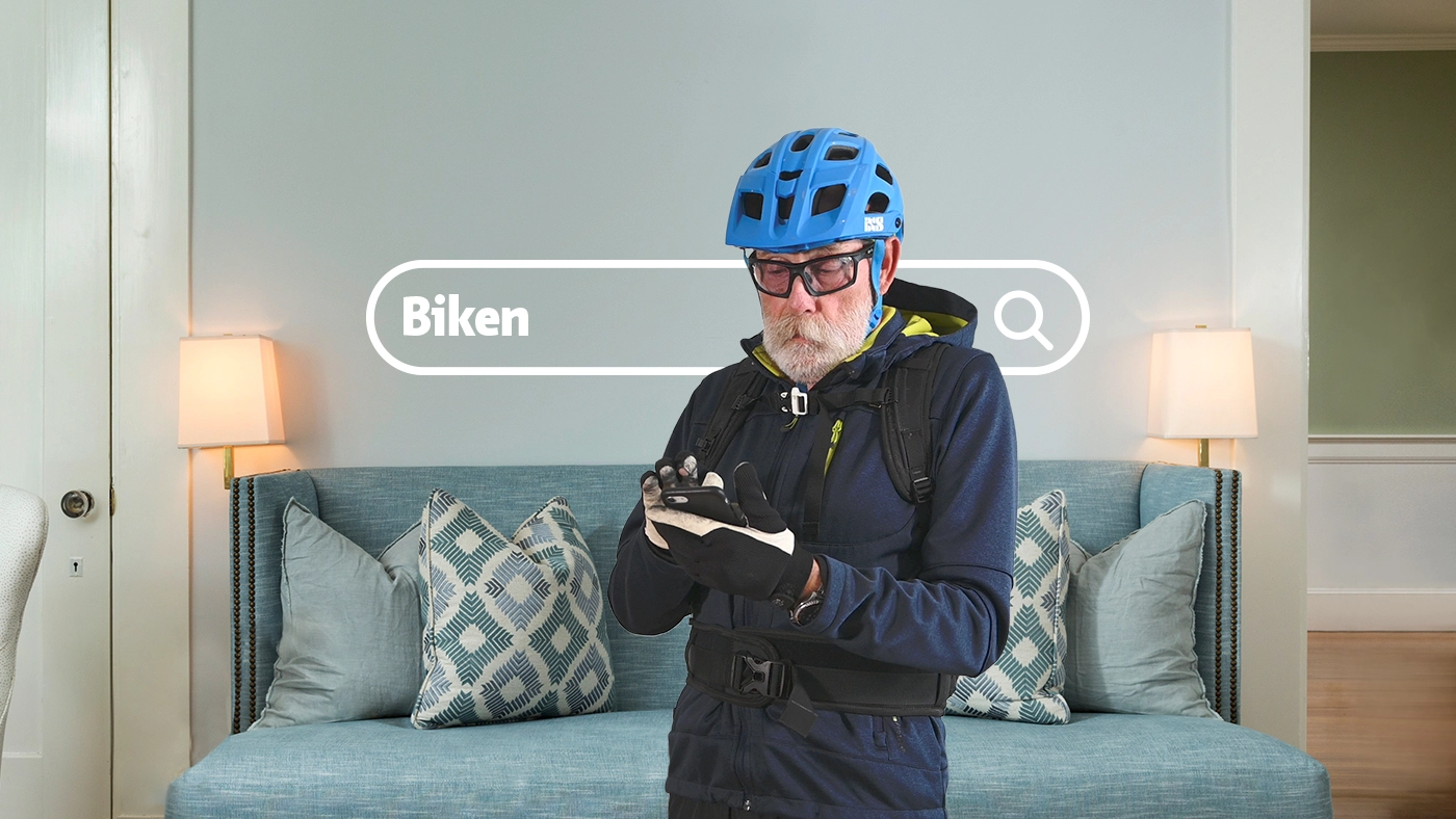 Ein Senior mit Bikehelm sucht auf seinem Smartphone nach passenden Kursen.